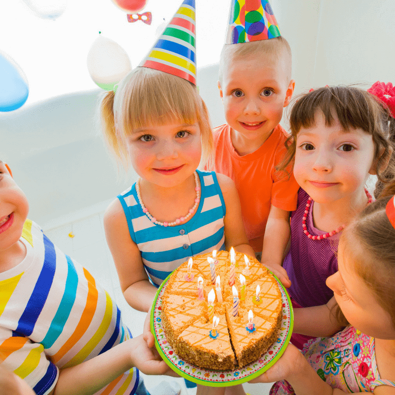 kids holding a birthday cake